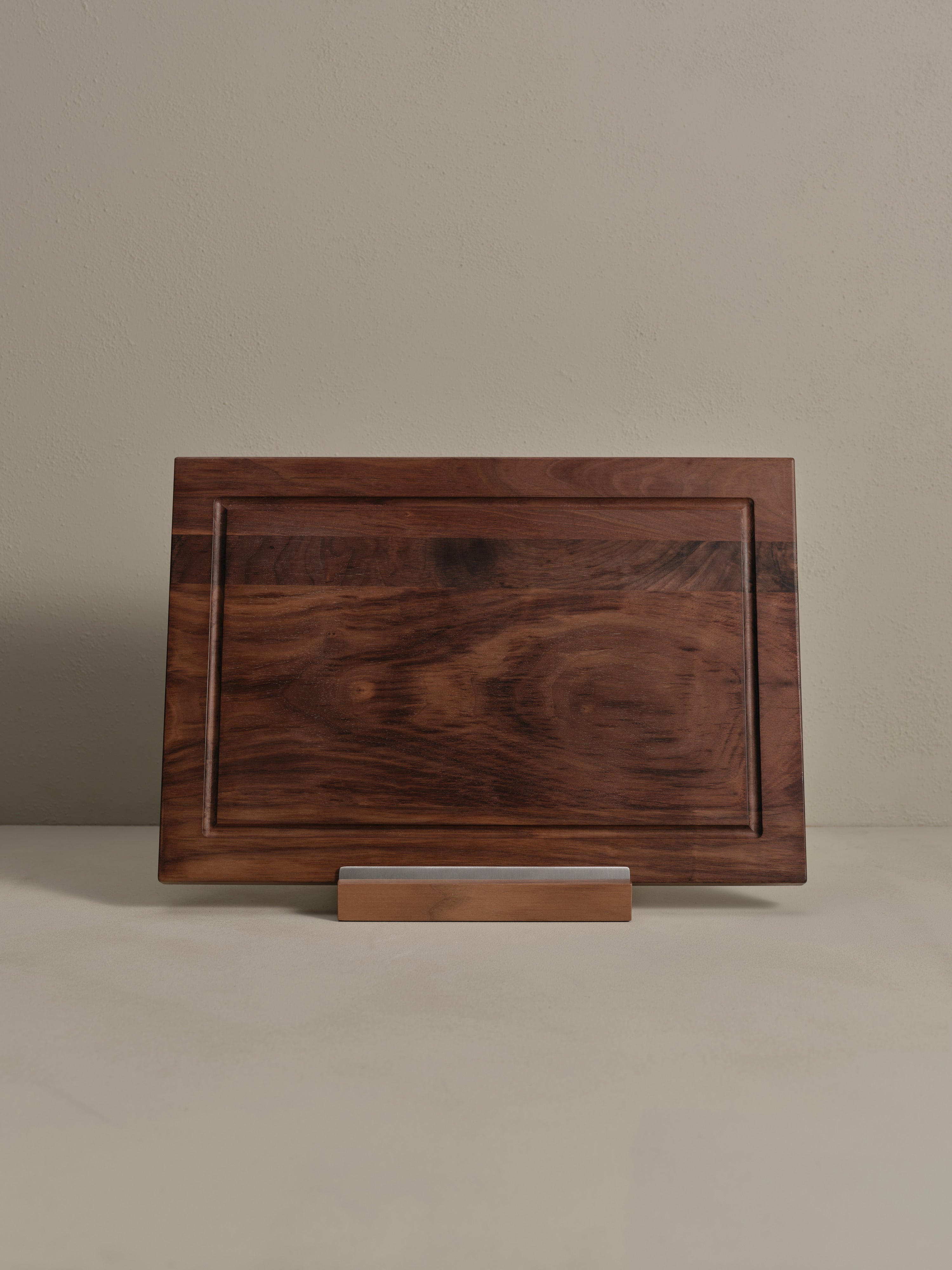 Katto walnut wood Chopping Board stood upright on its stand.