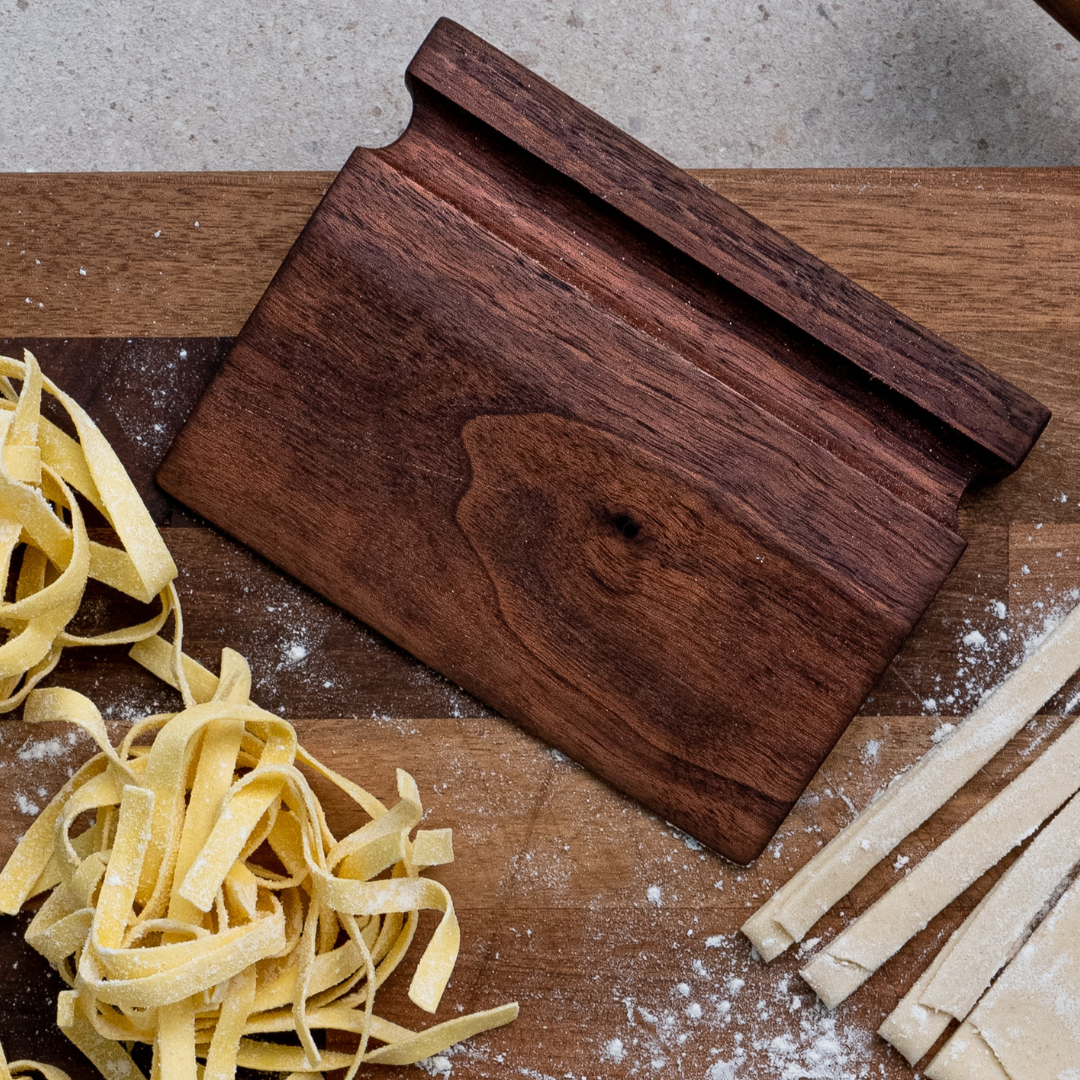 Katto walnut wood dough scraper on a chopping board amongst freshly made pasta